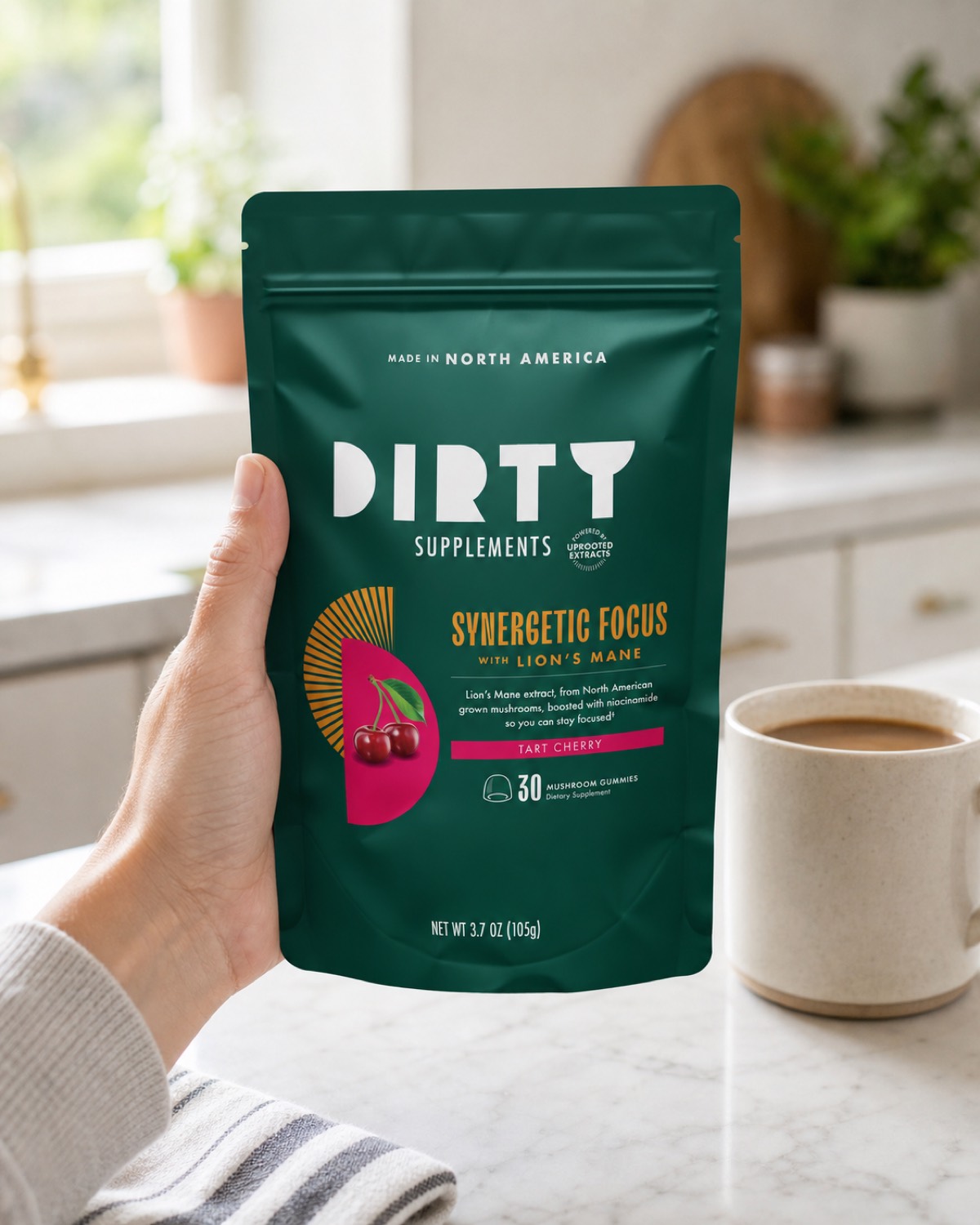 Hand holding a Synergetic Focus Lion's Mane gummy pouch beside a morning coffee